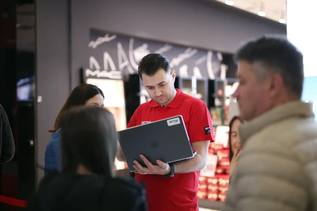 A store team member demonstrates an apple product to potential customers at a hi tech store