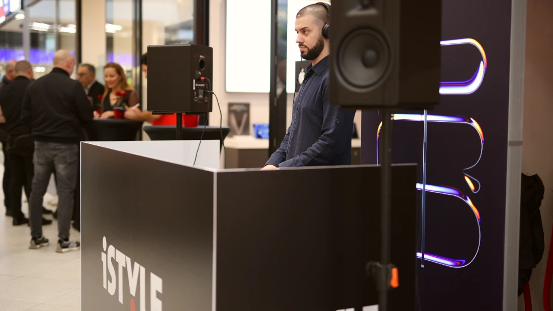 A DJ sits in his booth playing tunes outside a hi tech shop