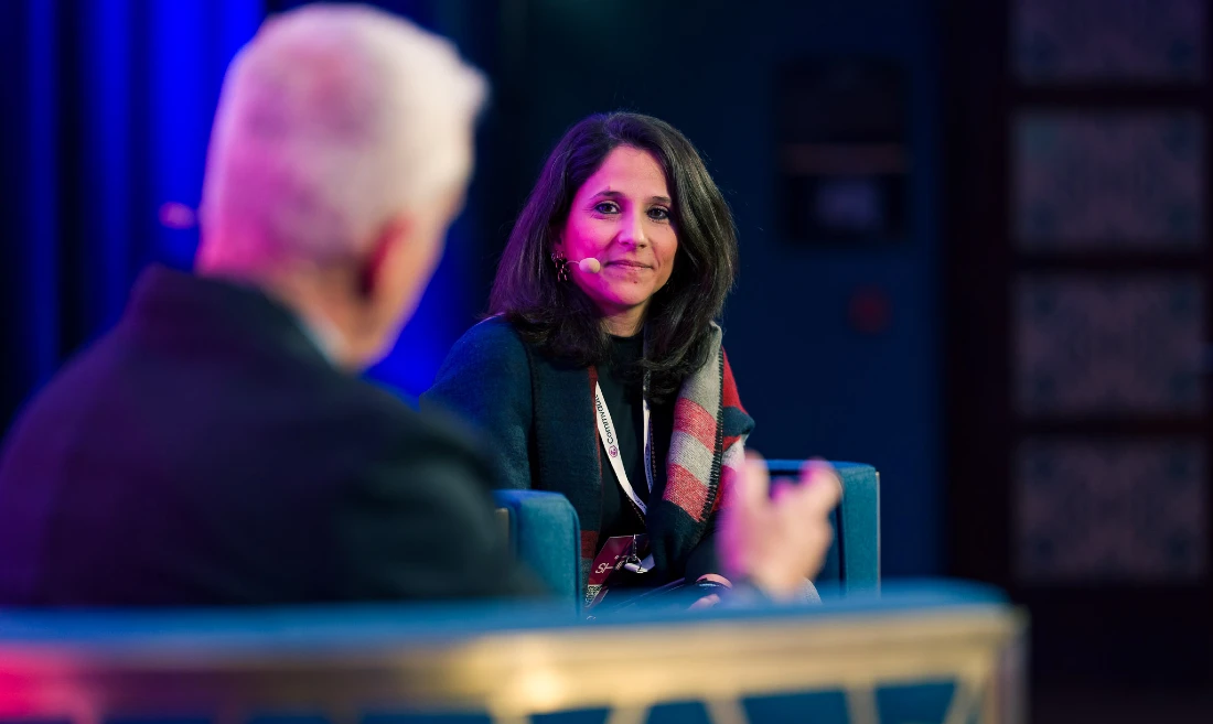 Une femme discute sur scène avec un homme lors d'une table ronde à un événement high-tech.