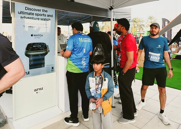 a young person wearing a runners medal is seen in front of the iSTYLE booth