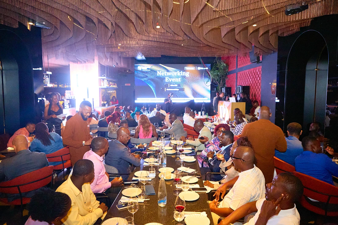 guests at an IT sector event are seen gathered around a dining table with a presentation screen at the end of the room