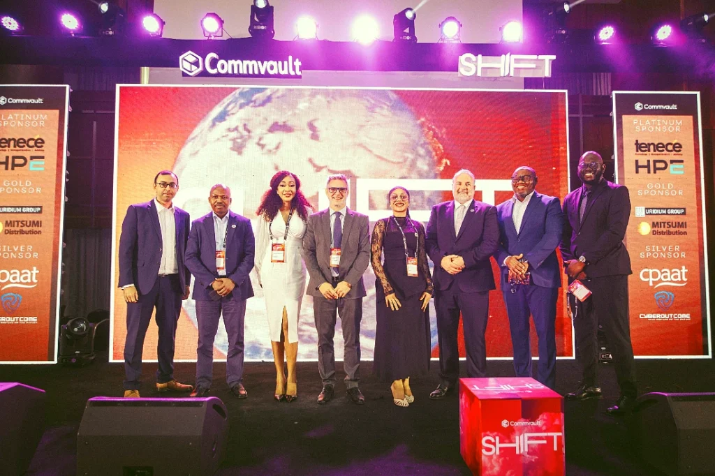 eight people in a group photograph on stage at a hi tech event
