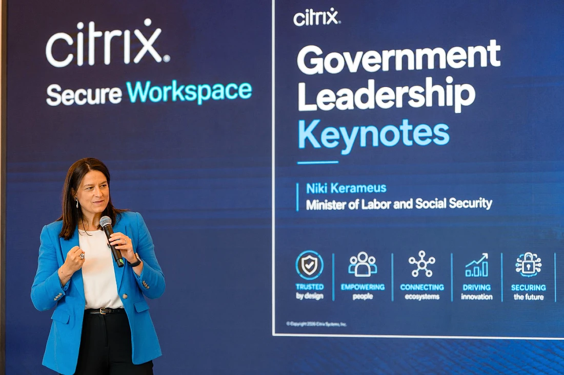 A woman in a blue jacket presents a keynote against a blue digital projection screen