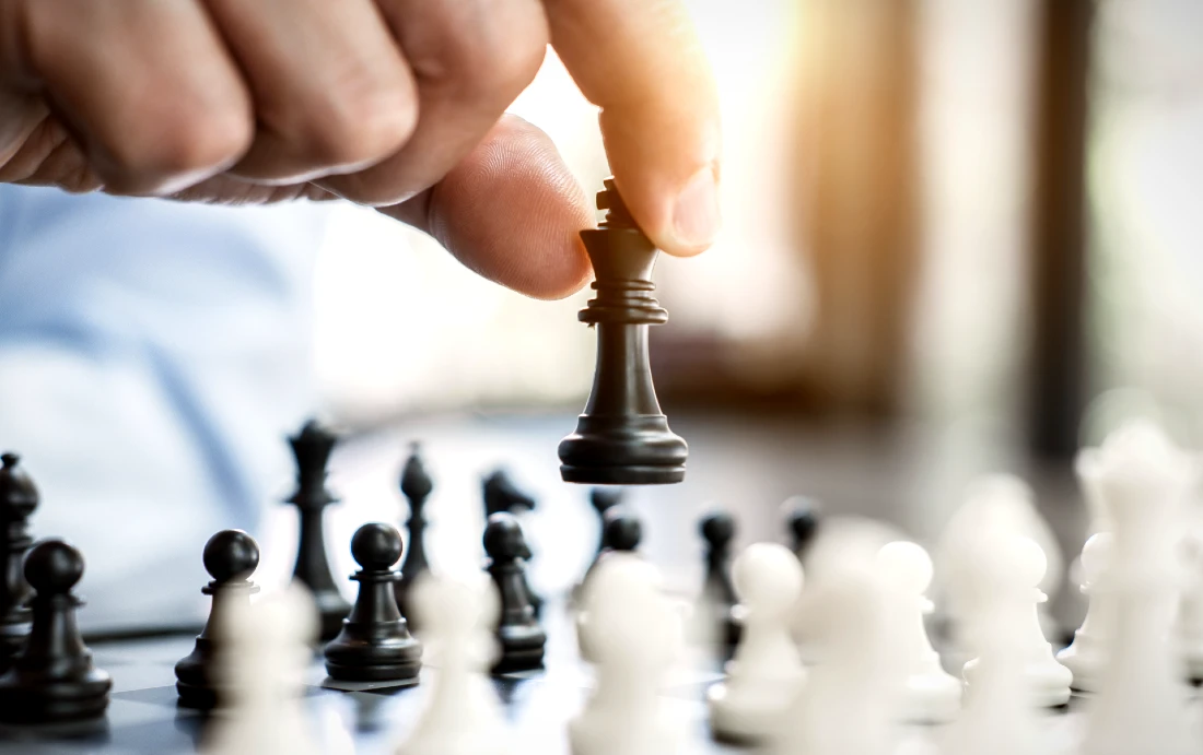 a close up image of a hand holding a chess piece above a chess board