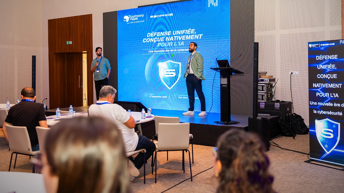 Two men on stage at a hi tech event, presenting to an audience